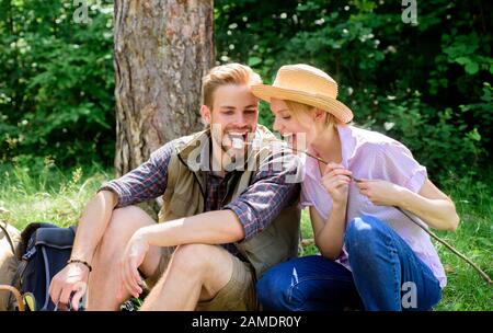 Couple dans l'amour camping forêt manger des guimauves rôties. Le marshmalloise à rôtir permet une activité de groupe populaire autour du feu de joie. Couple manger marshmallows rôtis snack nature fond. Activité de camping. Banque D'Images