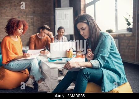 Un étudiant intelligent aux cheveux sombres se sentant concentré sur la langue d'apprentissage Banque D'Images