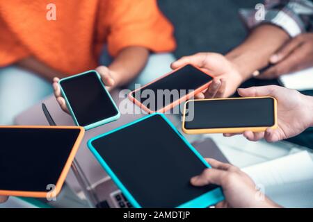 Les étudiants qui tiennent des smartphones et des tablettes lorsqu'ils utilisent des appareils Banque D'Images