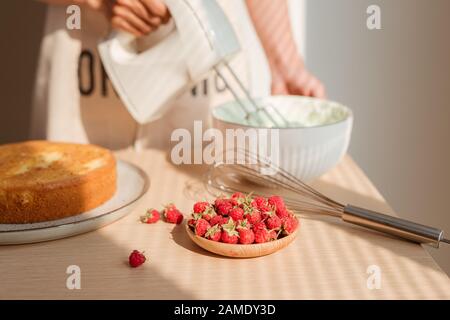 Fouetter la crème mains d'hommes blancs dans un bol en verre avec le mélangeur sur table en bois. Décisions ou gâteau Red Velvet Cake Banque D'Images