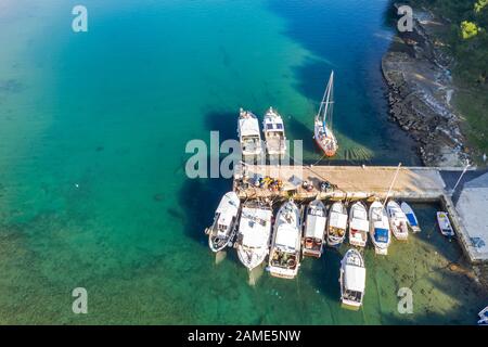 Une photo aérienne de la baie Runke avec petit port et jetée avec bateaux de pêche et équipement de pêche à Premantura, Istrie, Croatie Banque D'Images