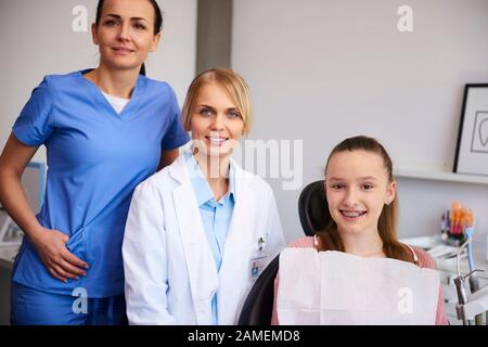 Portrait de deux orthodontistes souriants et d'un enfant au bureau du dentiste Banque D'Images