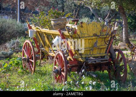 Jaune et rouge vintage panier wagon dans un jardin avec des vases et des plantes Banque D'Images