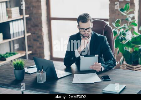 Photo de beau gars d'affaires focalisé sur la lecture e-Reader rapport de vérification des revenus de financement main toucher chin vêtements spécifications noir blazer chemise cravate Banque D'Images