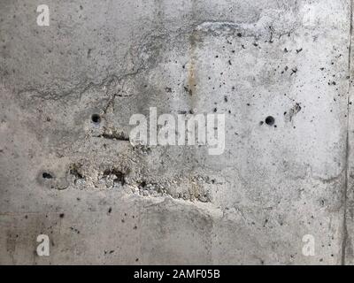 Surface en béton avec cavernes et pierres de gravier exposées et barres de renfort. Banque D'Images