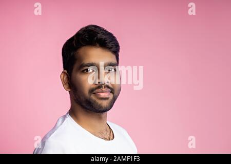 Portrait horizontal gros plan de beau jeune indien avec chaume, portant un t-shirt blanc, regardant l'appareil photo avec une expression sérieuse et calme, isolat Banque D'Images
