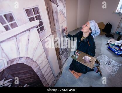 Femme artiste peint un mur dans un salon. La murale est dédiée aux impressions de Paris. Femme peint les détails, vue de dessus. Banque D'Images
