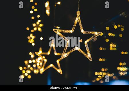 Des étoiles lumineuses et lumineuses de la guirlande sur un fond sombre et un beau bokeh. Décoration intérieure festive du nouvel an. Banque D'Images