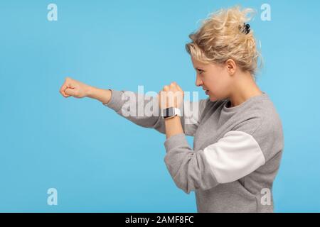 Prêt à se battre ! Vue latérale d'une femme féisteuse avec des cheveux courts en forme de carie dans un sweat-shirt pointant à côté avec une expression agressive en colère, défonce avec poing. I Banque D'Images