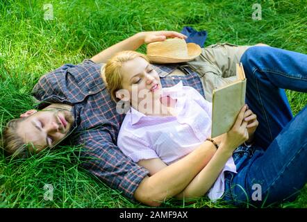 Couple romantique les étudiants apprécient les loisirs avec la poésie ou la littérature herbe arrière-plan. Couple soulmates à la date romantique. Couple amoureux passer le livre de lecture de loisirs. L'homme et la jeune fille se latent sur l'herbe s'amuser. Banque D'Images