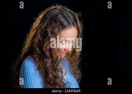 Jeune fille posant pour des photos de studio sur un fond noir, Banque D'Images