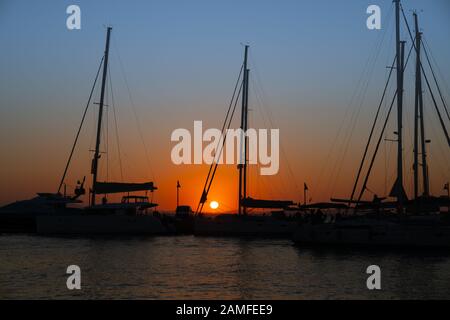 Lueur de coucher du soleil à travers le gréement de yachts amarrés à Naxos, l'île grecque. Banque D'Images