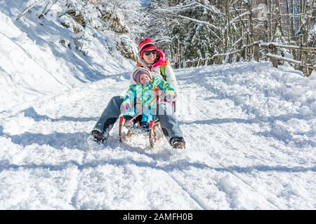 Mère et fille l'accélération en descente sur traîneau en bois. Banque D'Images