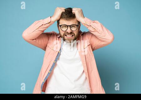 Homme barbu dans la colère et furieux, il essaie de déchirer ses cheveux sur la tête et les dents de rengrin. Banque D'Images