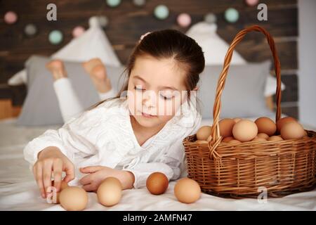 Fille qui s'amuse avec des œufs dans le lit Banque D'Images