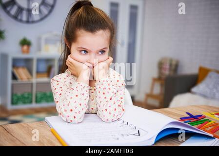 S'ennuyer et triste fille faisant des devoirs à la maison Banque D'Images