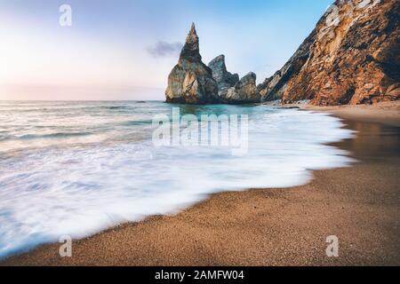 Plage De Portugal Ursa. Piles de mer, vague d'océan blanche éclairée par la lumière du coucher du soleil Banque D'Images