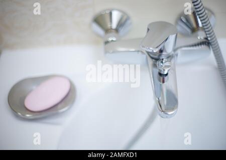 Robinet d'eau chromé et savon rose, vue de dessus. Robinet brillant dans la salle de bains. Banque D'Images