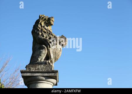 Un Lion au sommet d'un pilier calcaire contre le ciel bleu dans les jardins de Polesden Lacey, Great Bookham, Surrey, Angleterre, janvier 2020 Banque D'Images