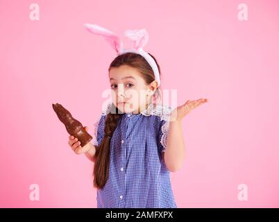 Une fille confuse mangeant un lapin au chocolat en studio Banque D'Images