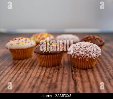 18 Fermez et concentrez-vous sur un cupcake au chocolat entre autres cupcakes sur un fond en bois Banque D'Images