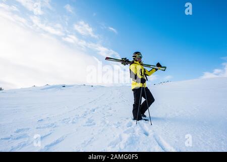 sportif dans un casque debout avec des bâtons de ski sur la neige dans les montagnes Banque D'Images