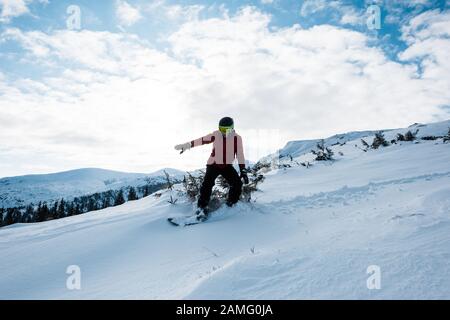 snowboarder dans des lunettes et un casque qui monte en pente en hiver Banque D'Images