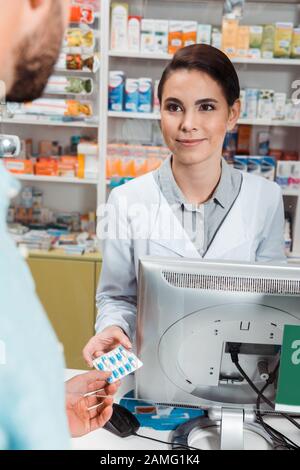 Foyer sélectif de sourire drogiste donnant des pilules au client au comptoir de pharmacie Banque D'Images