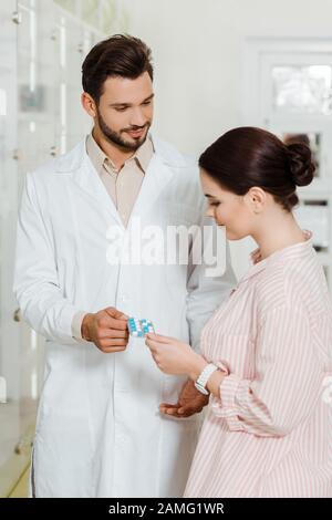 Handsome droggist donnant des pilules au client dans la pharmacie Banque D'Images