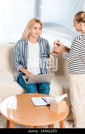 mère regardant la fille tout en prenant un verre d'eau Banque D'Images