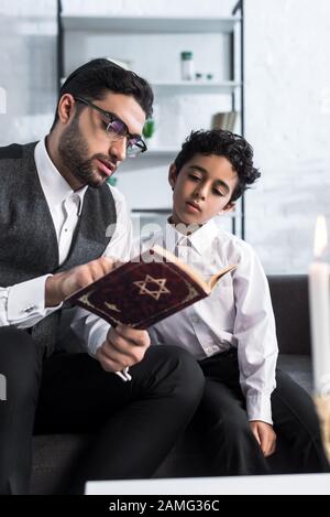 beau père juif et fils lisant tanakh dans l'appartement Banque D'Images