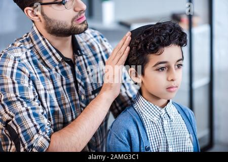 vue courte du père juif portant un chapeau sur son fils dans l'appartement Banque D'Images