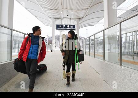 (200113) -- BEIJING, le 13 janvier 2020 (Xinhua) -- Xiao Zhen (R) tenant des planches à ski et des bâtons marche avec son ami à son arrivée à la gare de Taizicheng sur la ligne de chemin de fer à grande vitesse Beijing-Zhangjiakou dans le district de la ville de Zhangjiakou, dans la province de Hebei au nord de la Chine, le 11 janvier 2020. Xiao Zhen, un membre du personnel d'une société Internet de Pékin, est passionné de ski depuis quatre ans et se rend toujours dans les domaines skiables du district de Xingjiakou, dans la province de Hebei en Chine du nord. Selon Xiao, Elle avait l'habitude de passer quatre à cinq heures à pied à un ascenseur ou à prendre un bus pour se rendre à Chongli de Pékin. Banque D'Images