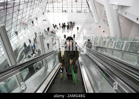 (200113) -- BEIJING, le 13 janvier 2020 (Xinhua) -- Xiao Zhen tenant des planches à ski et des poteaux prend un escalator à la gare de Qinghe sur la ligne ferroviaire à grande vitesse Beijing-Zhangjiakou à Beijing, capitale de la Chine, le 11 janvier 2020. Xiao Zhen, un membre du personnel d'une société Internet de Pékin, est passionné de ski depuis quatre ans et se rend toujours dans les domaines skiables du district de Xingjiakou, dans la province de Hebei en Chine du nord. Selon Xiao, Elle avait l'habitude de passer quatre à cinq heures à pied à un ascenseur ou à prendre un bus pour se rendre à Chongli de Pékin. La récente opération de la ligne ferroviaire à grande vitesse Beijing-Zhangjiakou RE Banque D'Images