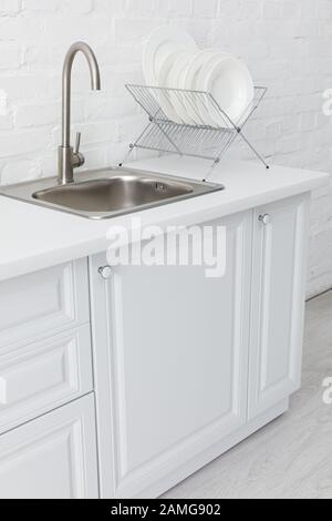 intérieur minimaliste moderne de cuisine blanche avec évier et plaques sur le stand près du mur de brique Banque D'Images