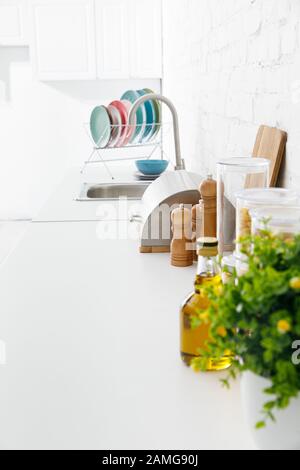 foyer sélectif intérieur moderne de cuisine blanche avec ustensiles de cuisine et plante verte près du mur de brique Banque D'Images