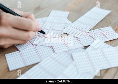 vue rognée d'une femme tenant le stylo près des billets de loterie sur la table Banque D'Images