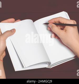 Les mains des hommes tiennent un carnet blanc avec des pages propres et un crayon noir Banque D'Images