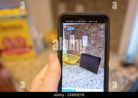 Main d'un homme tenant un smartphone et utilisant les fonctionnalités De Réalité augmentée dans l'application Amazon shopping pour visualiser un appareil Amazon Echo Show sur un comptoir de cuisine, San Ramon, Californie, 22 novembre 2019. L'AR est de plus en plus utilisée comme une fonctionnalité pour les consommateurs de visualiser les produits dans leur maison avant de prendre une décision d'achat. () Banque D'Images