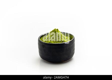 Isolez la poudre de thé vert tas dans un bol en céramique noire. Extraire Les Feuilles de thé dans une tasse en pierre sombre. Banque D'Images