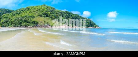 Plage touristique brésilienne sur une journée ensoleillée. Vue panoramique sur une plage avec une mer calme et quelques vagues à Praia do Guaiuba plage - Guaruja SP Brésil. Banque D'Images