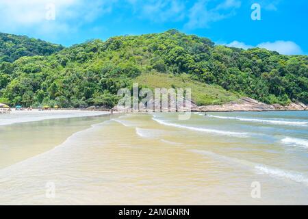Plage touristique brésilienne sur une journée ensoleillée. Vue sur une plage avec peu de personnes, mer calme et quelques vagues à Praia do Guaiuba plage - Guaruja SP Brésil. Banque D'Images