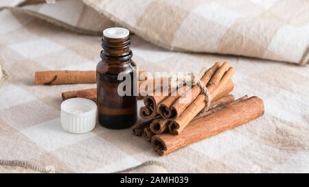 Composition cosmétique, des bâtons de cannelle et une bouteille en verre à l'huile essentielle sur la table Banque D'Images