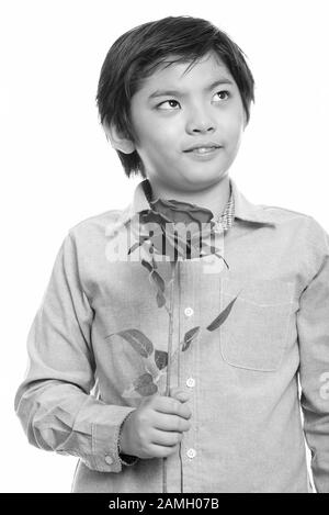 Studio shot of cute Japanese boy holding red rose et la pensée Banque D'Images