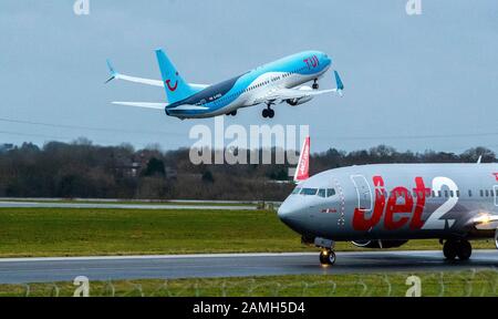 Un Boeing 737-8K5 TUI avec enregistrement G-FDZS prend le départ de l'aéroport de Manchester comme un Boeing 737-8K5 Jet2 avec l'enregistrement G-JZHC taxis passé. Photo PA. Date De L'Image: Lundi 13 Janvier 2020. Crédit photo devrait lire: Peter Byrne/PA Wire Banque D'Images