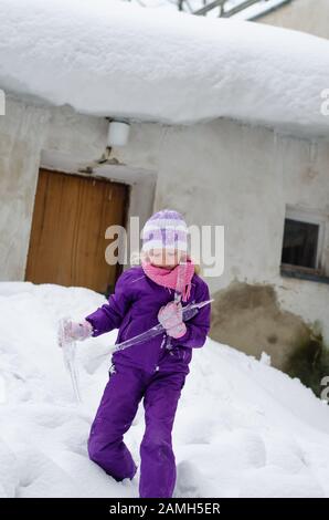 adorable fille avec de longs cheveux s'amuser avec des icones congelés dans les merveilles enneigées Banque D'Images