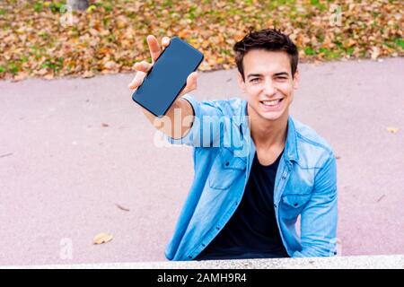 Jeune homme Montrant un Écran noir Vide de son téléphone portable à l'appareil photo en gros plan Banque D'Images