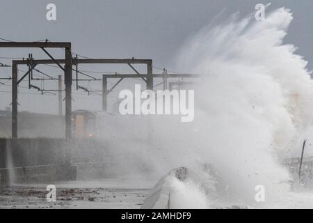 Saltcoats, North Ayrshire, Ecosse, Royaume-Uni - 13 janvier 2020: Météo au Royaume-Uni: Un train passe par des vagues massives à Saltcoats aujourd'hui cet après-midi. Cette section de la ligne de chemin de fer a été fermée peu après Banque D'Images