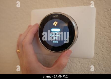 Gros plan de la main d'un homme passant en mode chauffage sur un Nest Learning thermostat, un Internet des Objets de Google Inc, dans une maison intelligente à San Ramon, Californie, 17 décembre 2019. () Banque D'Images