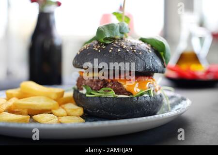 Hamburger noir. Un délicieux hamburger dans un rouleau noir. Banque D'Images